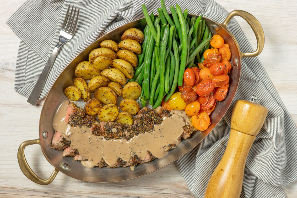 Pepper crusted steak topped with sauce from Rubix Foods.